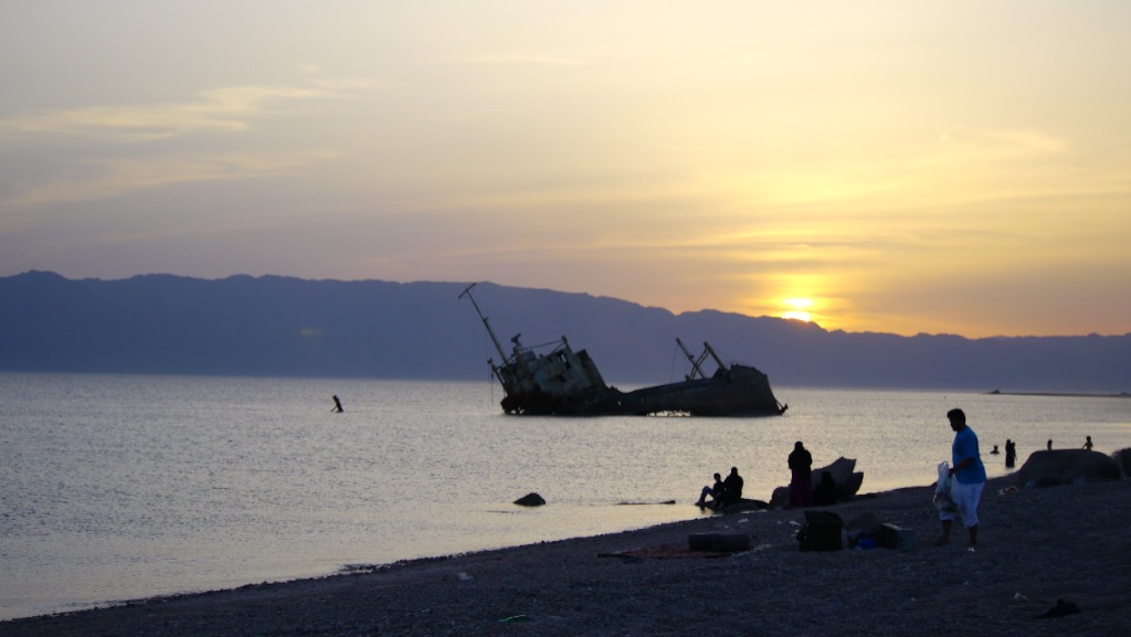 People on the beach at dusk, the wreck out in the bay